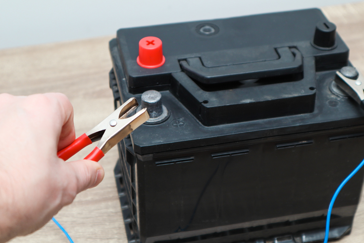 Charging car battery with electric current. Close up of hand Charging car battery with electricity trough jumper cables